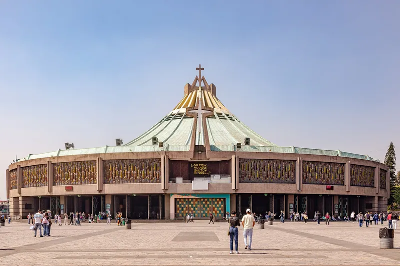 A basílica moderna de Guadalupe, de planta circular e teto verde, diante de uma grande praça.