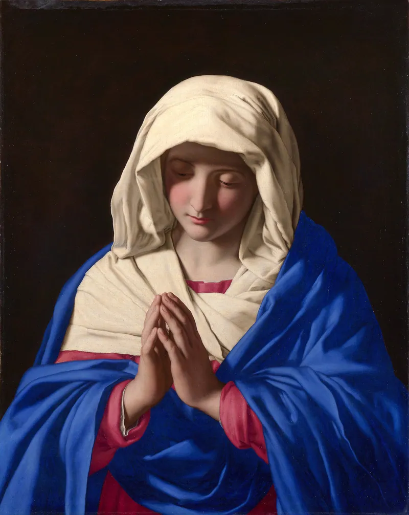 Pintura de Maria em oração: véu claro sobre a cabeça, manto azul, mãos postas e olhos baixos, diante de um fundo escuro.