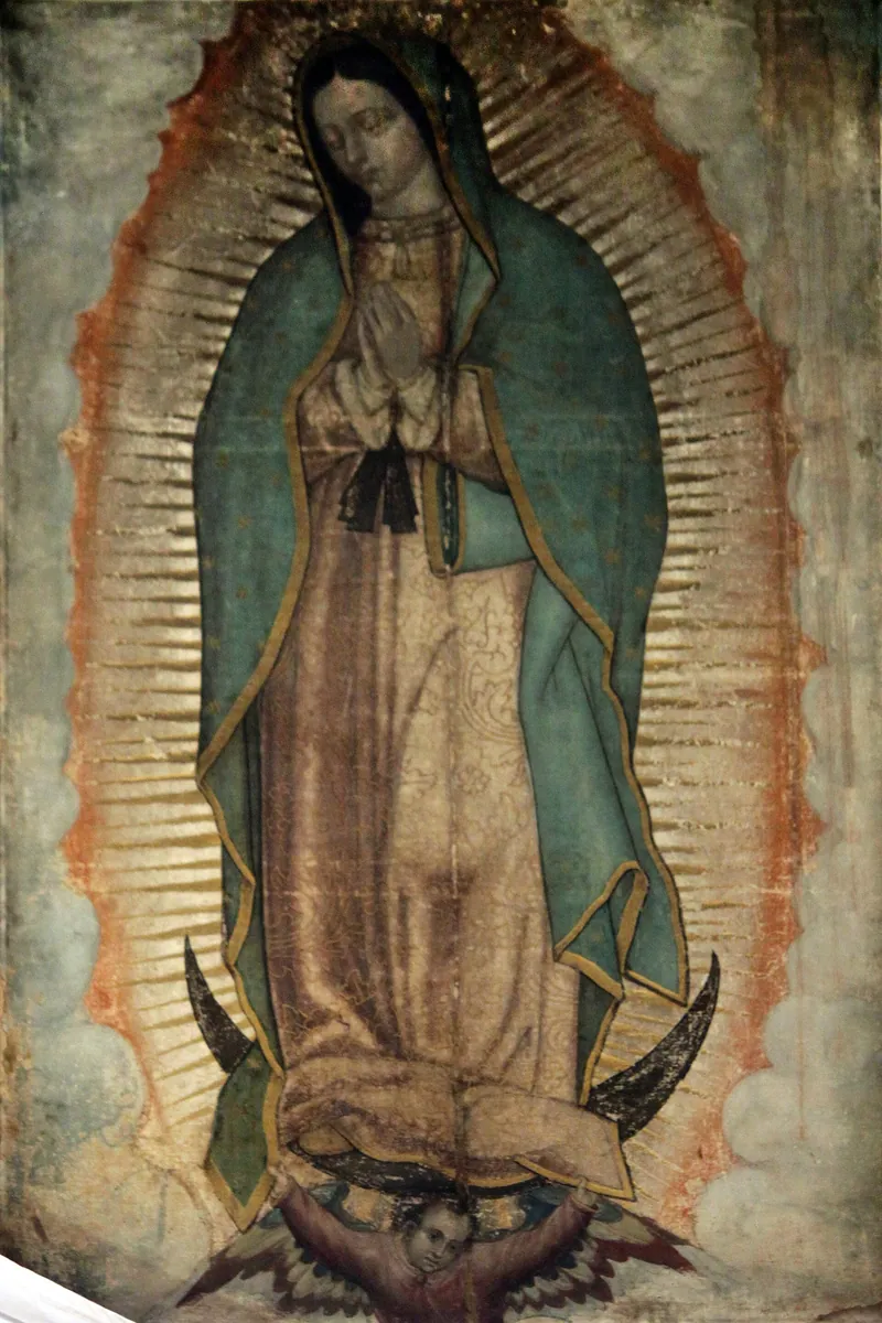 Maria de pé sobre a lua, com manto azul-esverdeado coberto de estrelas, mãos postas e raios dourados ao redor, sustentada por um anjo.